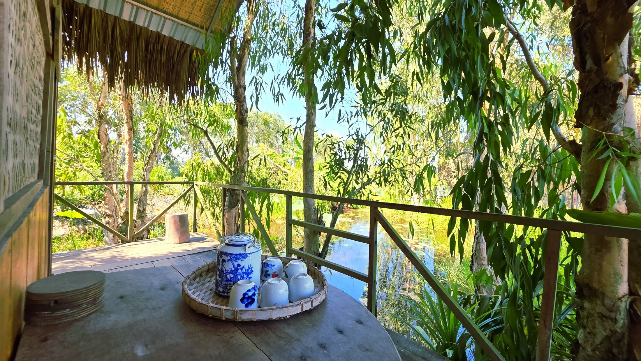 Tea set on a bungalow veranda facing trees and water